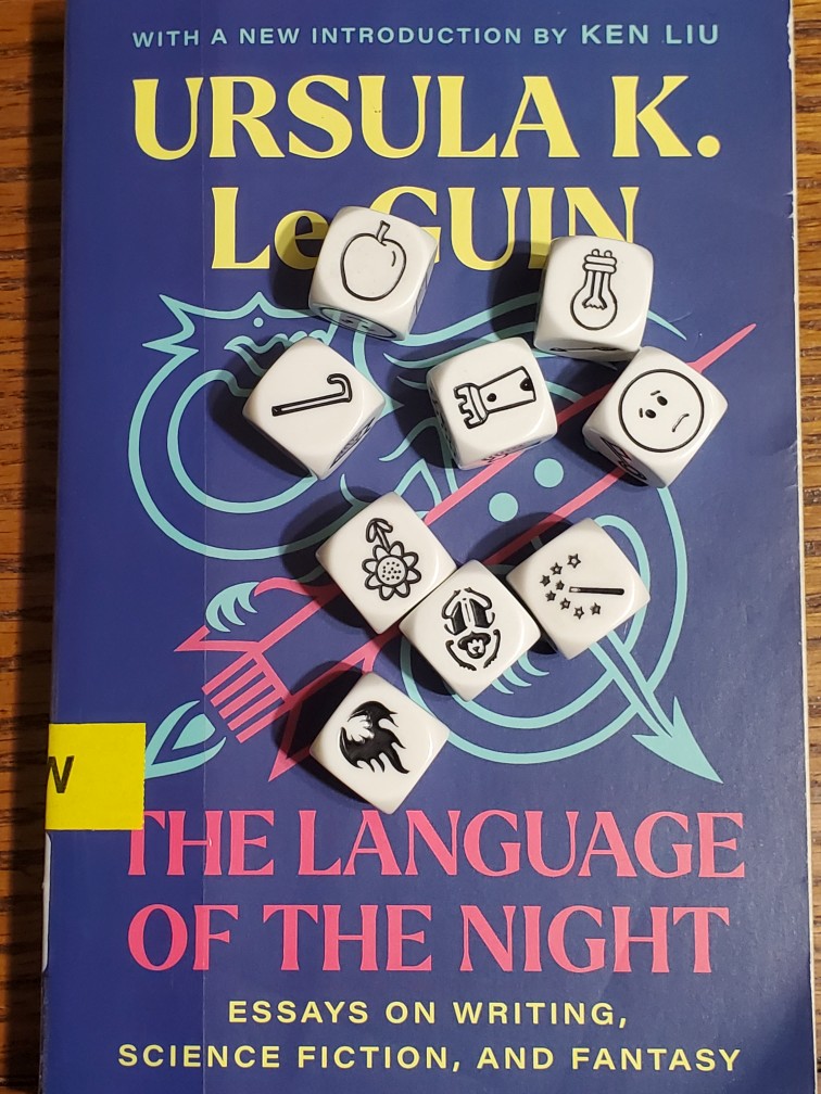 Story Cubes on top of "The Language of the Night" by Ursula K. Le Guin